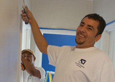 A Man Smiling and Working on a Wall Image